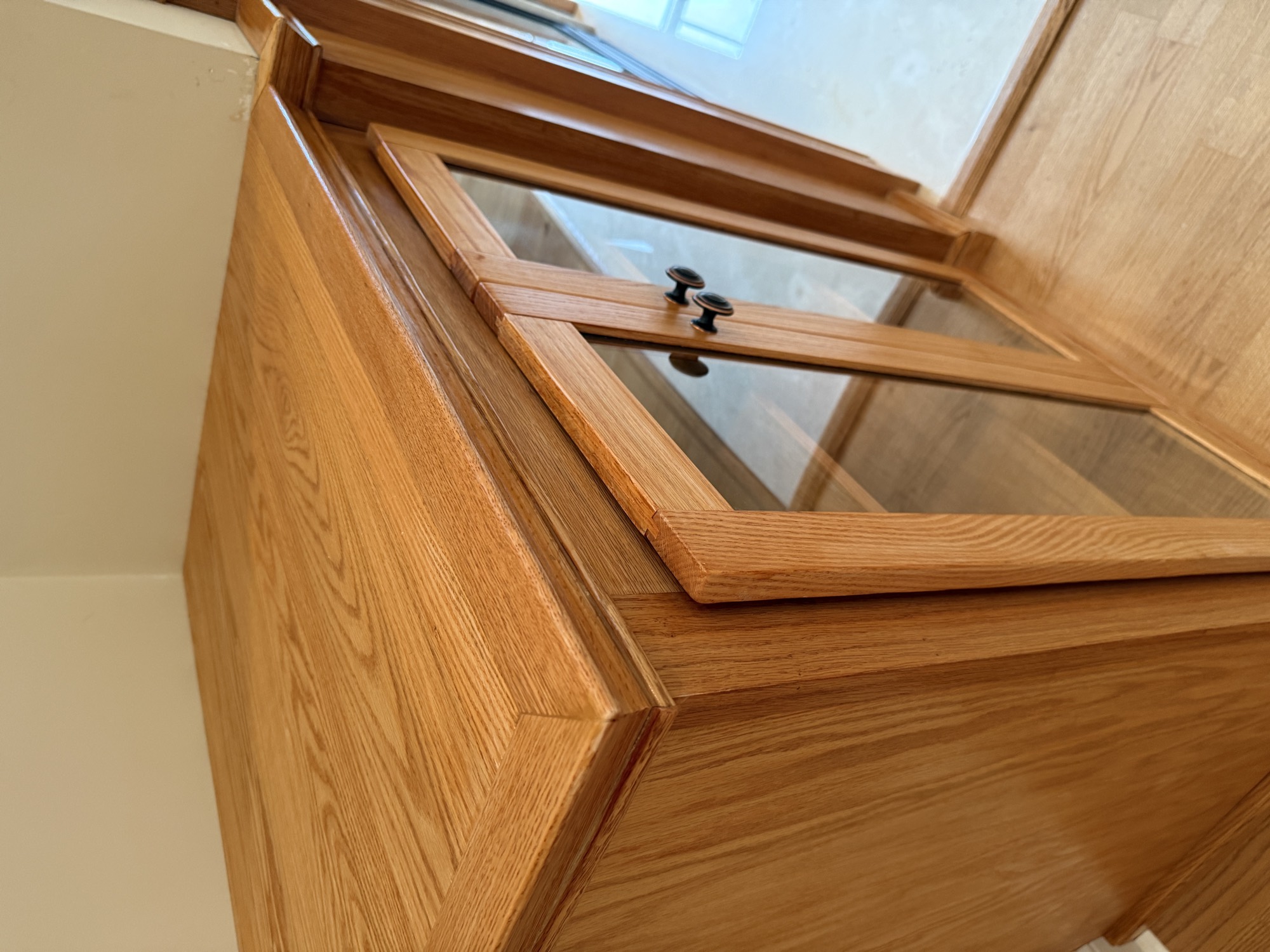 Close-up of the oak cabinet top, cap moulding and door frame showing grain and finish color