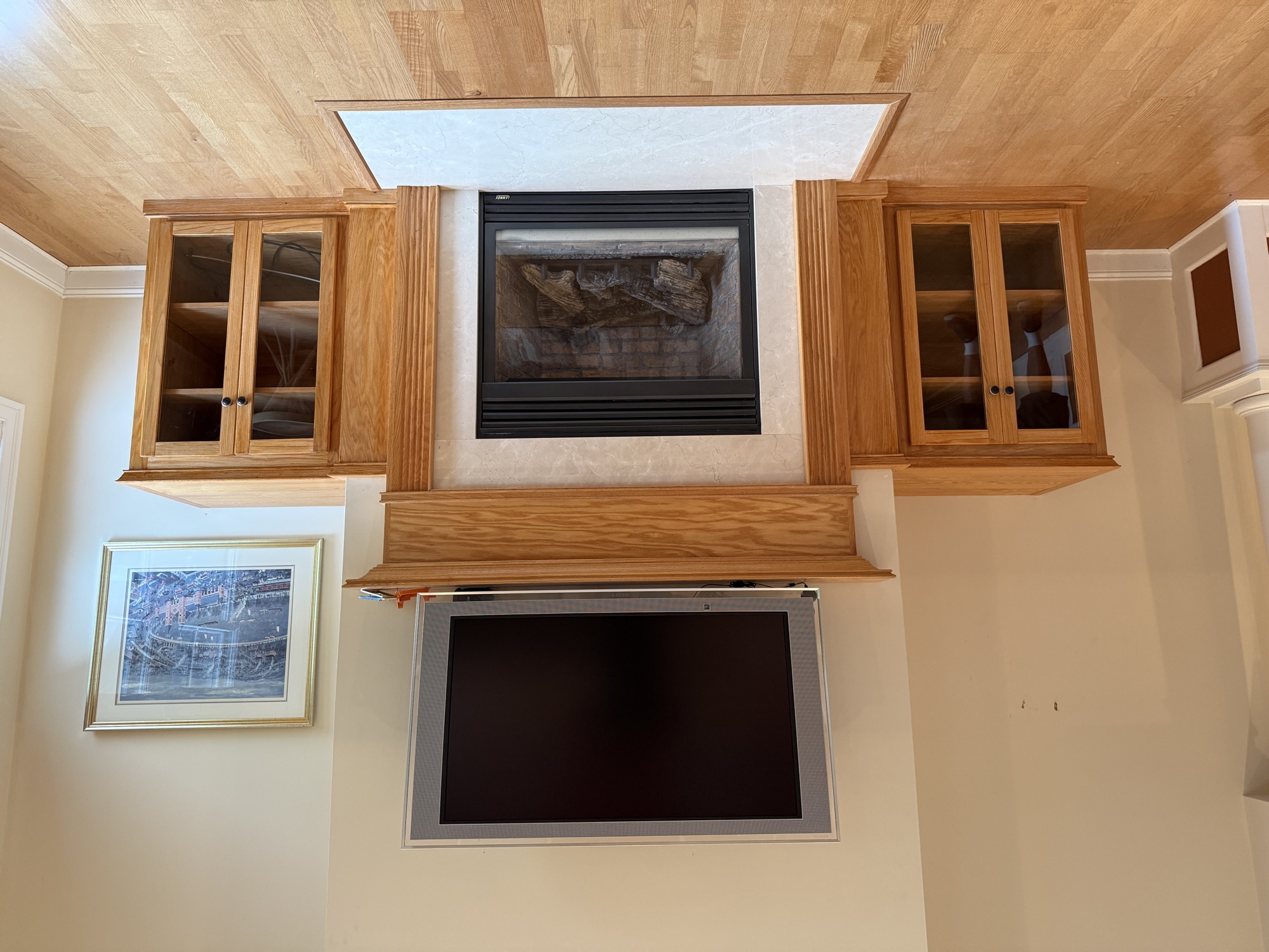 Custom oak fireplace built-ins with glass-front cabinets flanking an existing oak mantle in a Narragansett, RI living room