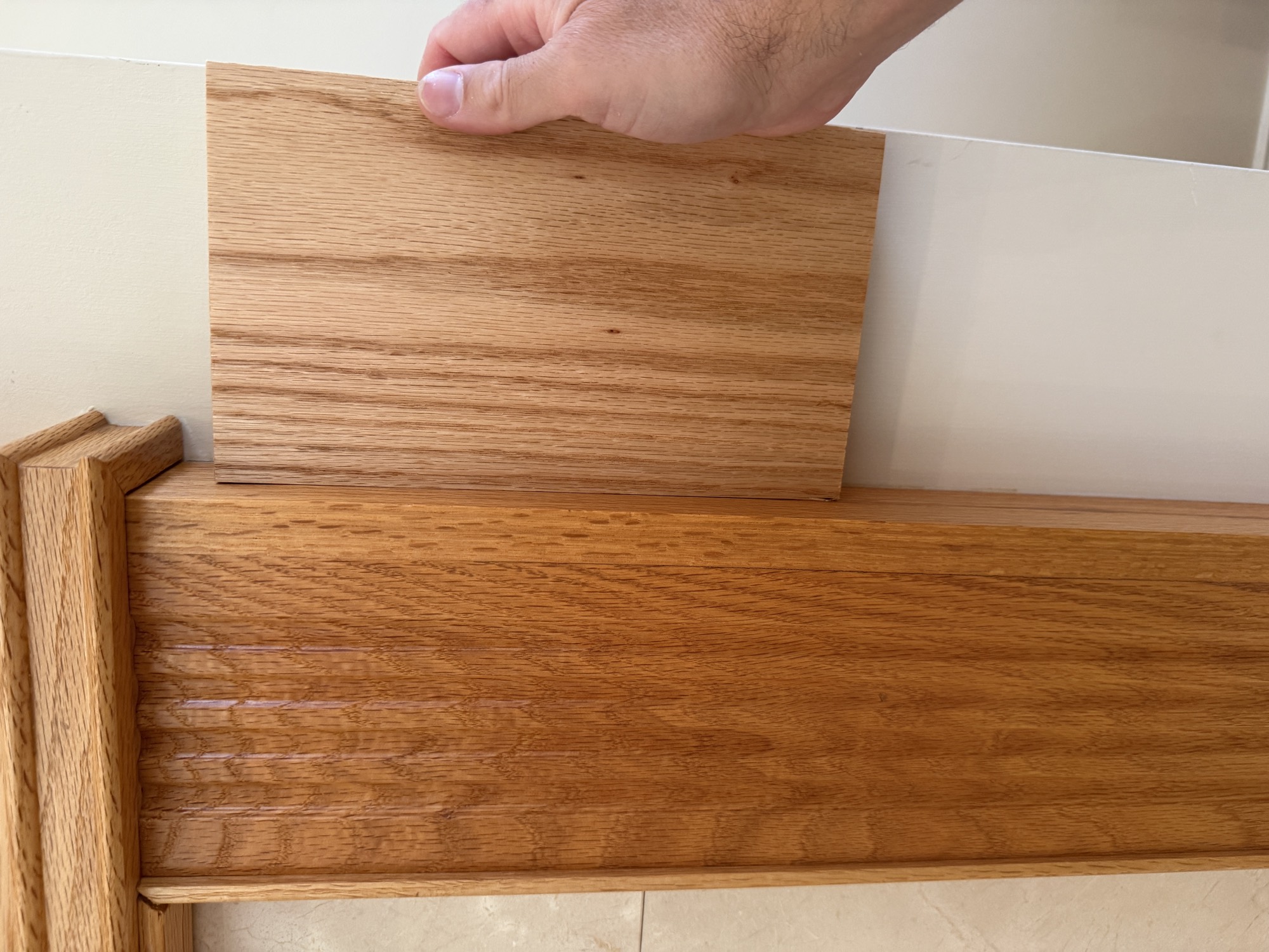 A sample board of new oak held against the existing aged oak fireplace mantle to compare color