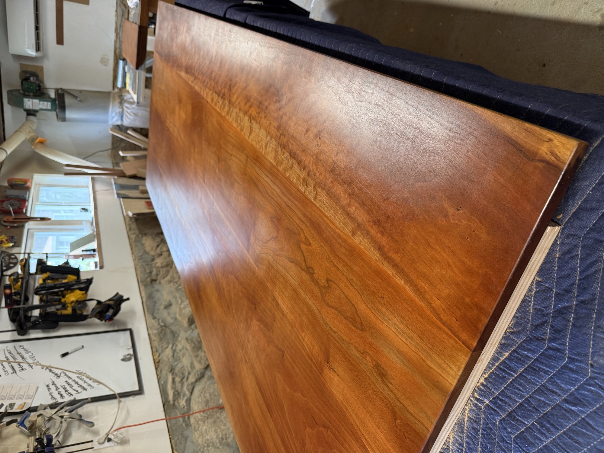 Full length of a refinished hardwood dining tabletop on a bench in the shop