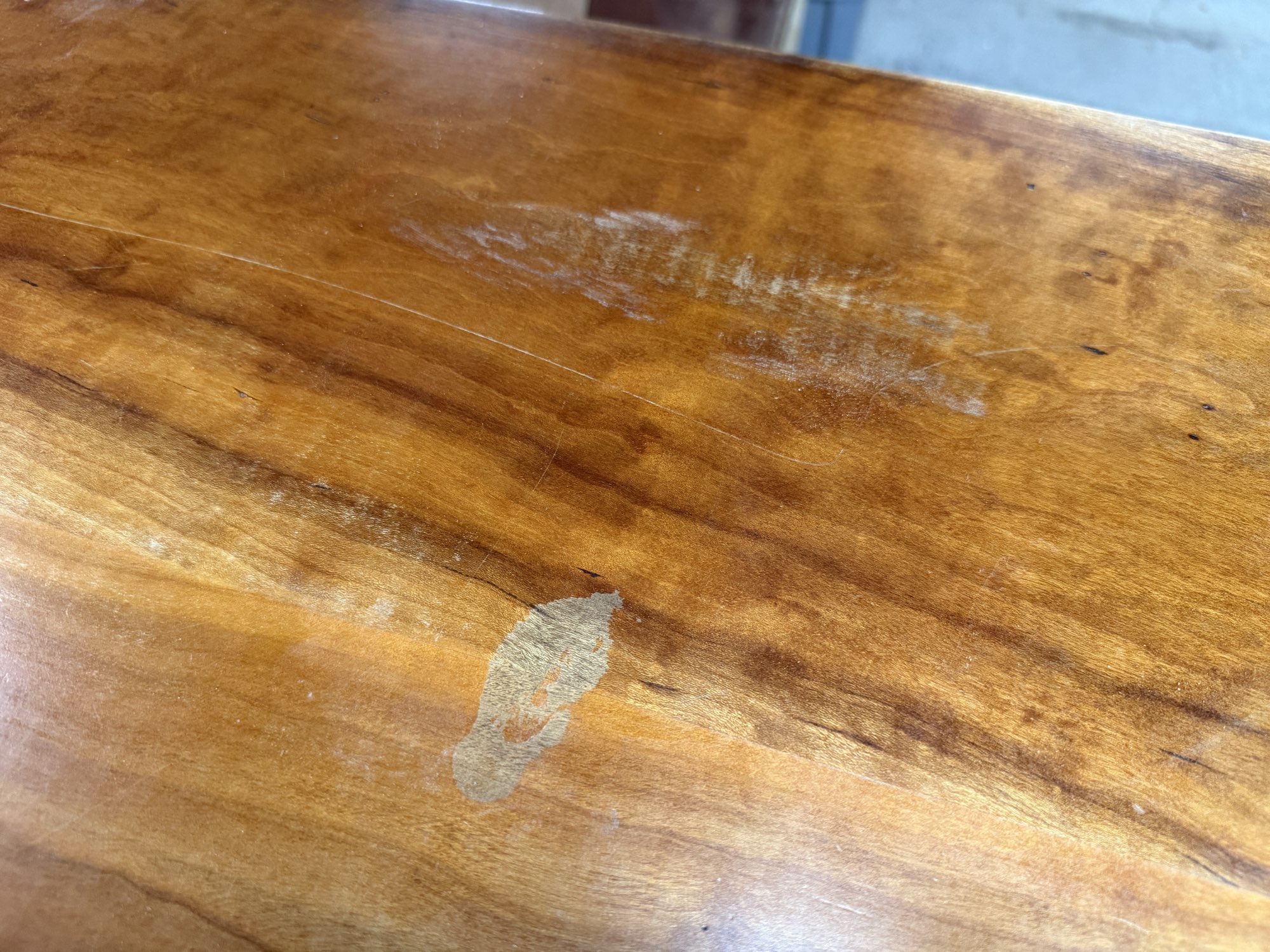 Dark stain and white worn patches in the old finish on a Wakefield dining tabletop before refinishing